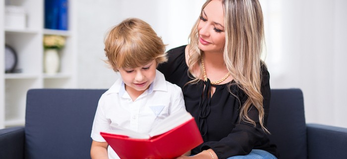 A boy reading a book with his mom