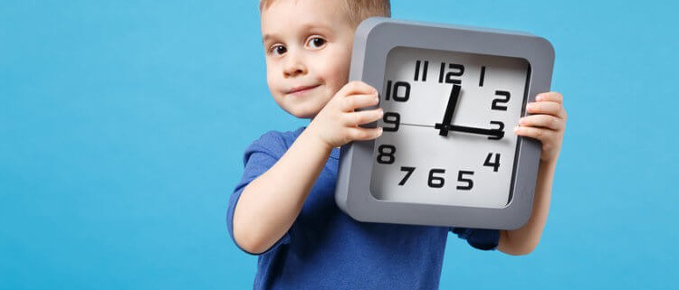 a young boy holding a analog clock