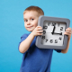 a young boy holding a analog clock