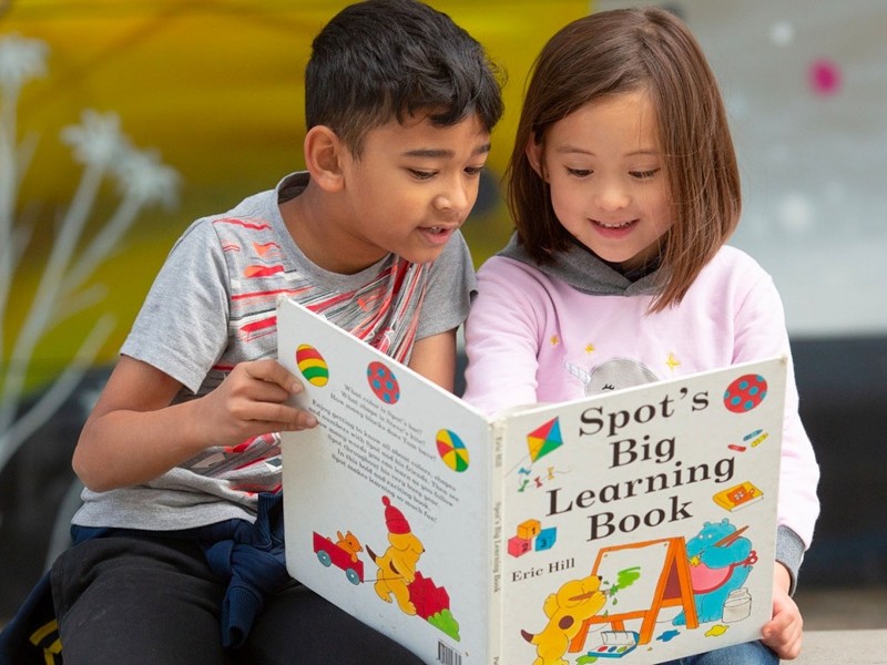 Two kids sharing a book